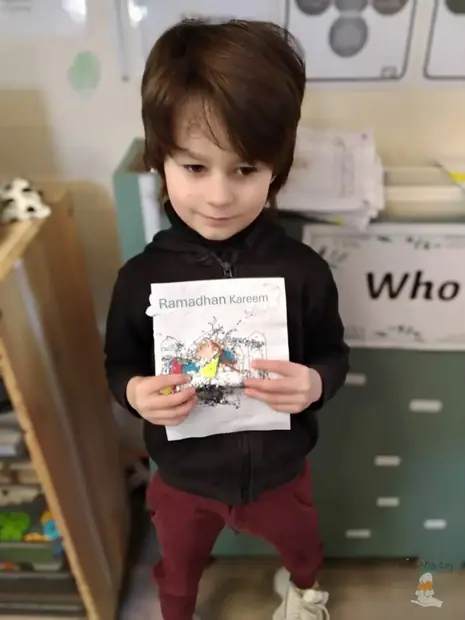 A smiling boy holding up his work